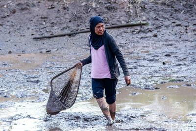 Woman fishing in a muddy pond