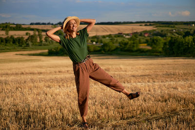 Full length of smiling woman standing on land against sky