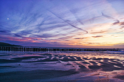 Scenic view of beach against sky at sunset