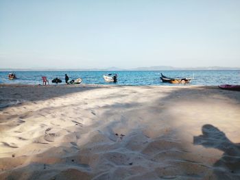 People on beach against clear sky