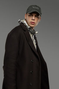 Portrait of young man standing against gray background