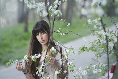 Portrait of woman amidst flowering tree at park