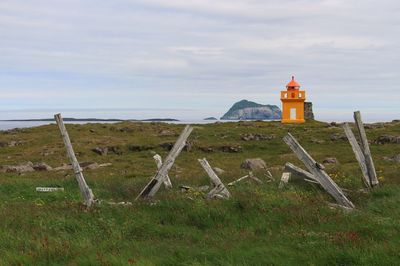 Lighthouse on field against sky