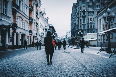 Rear view of people walking on city street