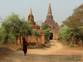 Rear view of woman walking in temple against sky