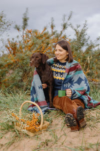 Portrait of young woman with dog on field