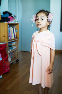 A little girl is standing in a beautiful dress with hair accessories. pretend play at home.