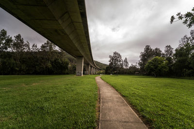 Footpath by bridge against sky