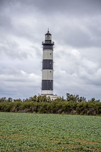 Lighthouse on landscape against sky