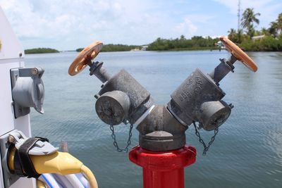 Close-up of coin-operated binoculars by river against sky