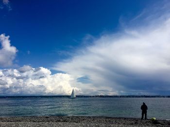 Rear view of man standing on beach against sky