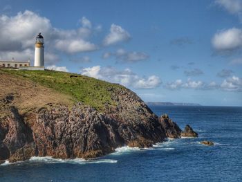 Lighthouse by sea against sky