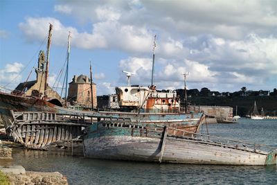 Sailboats in river by buildings against sky