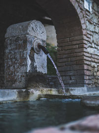 Water fountain against brick wall