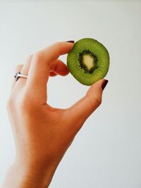 Cropped image of woman holding leaf over white background