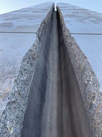 Low angle view of concrete wall by sea against sky