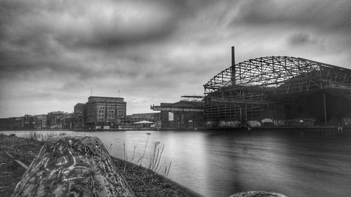 View of buildings by river against cloudy sky
