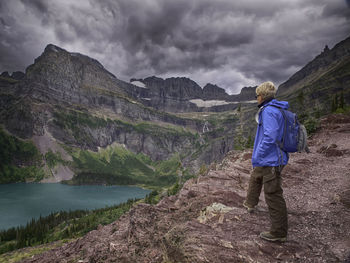 Man standing on mountain against cloudy sky