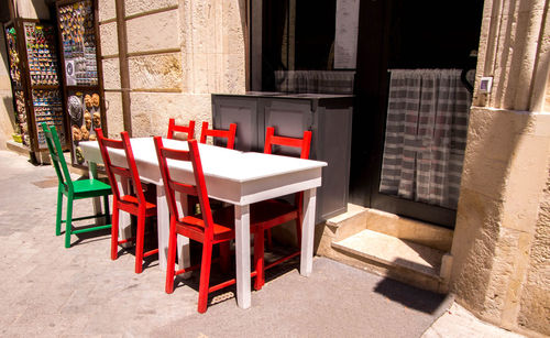 Empty chairs and tables in cafe against building