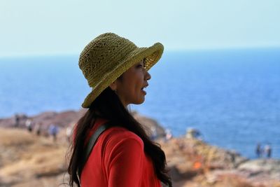 Side view of young woman standing against sea