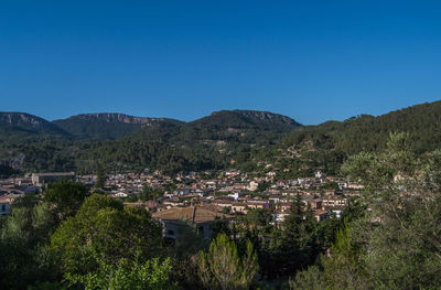 Town by mountains against clear blue sky