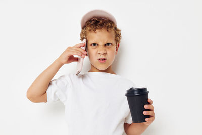 Angry boy talking on phone against white background