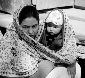 Portrait of happy mother and daughter sitting outdoors