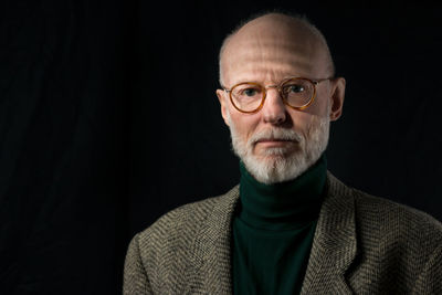 Portrait of senior man wearing eyeglasses against black background