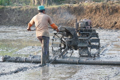 Rear view of man working in water