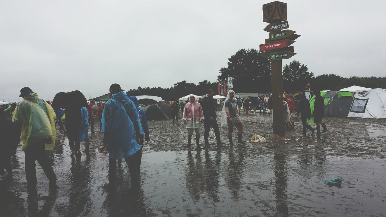 water, men, lifestyles, leisure activity, sky, person, large group of people, walking, standing, full length, outdoors, built structure, day, umbrella, clear sky, rear view, reflection, medium group of people, building exterior