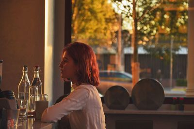 Woman looking away while sitting in bar