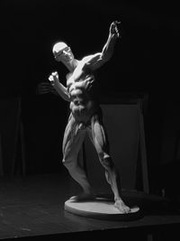 Statue of muscular build naked man against black background