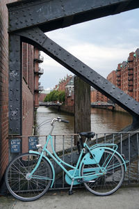 Bicycle on bridge over river against buildings