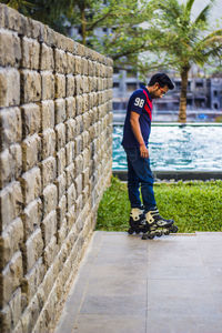 Side view of man inline skating by wall at resort