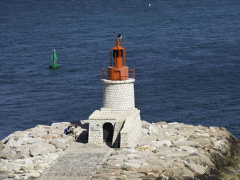 Lighthouse by sea against buildings