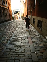 Rear view of woman walking with dog in city