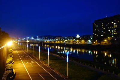 Illuminated bridge over road against sky at night