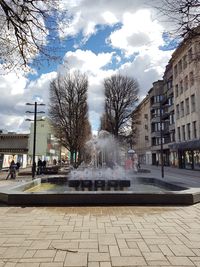 Bare trees in city against sky