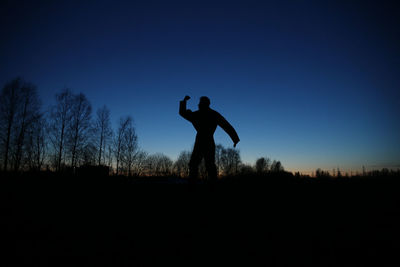 Silhouette man standing on field against sky during sunset