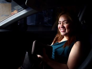 Portrait of woman smiling while sitting in car