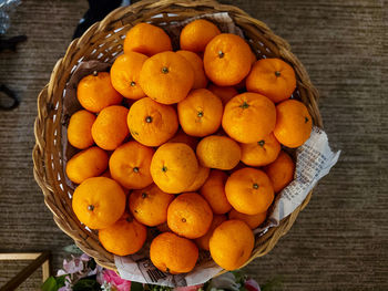 High angle view of orange fruits in basket on table.