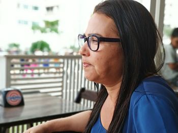 Side view of mature woman looking away while sitting in cafe