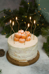 Homemade christmas cake with fir branches, candles on gray background.