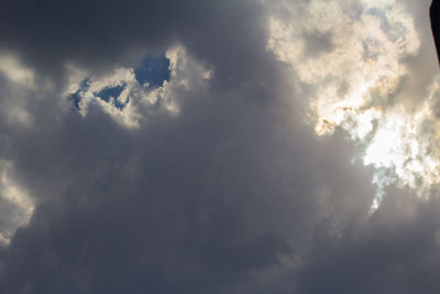 Low angle view of sunlight streaming through clouds