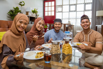 Portrait of smiling friends having food at home