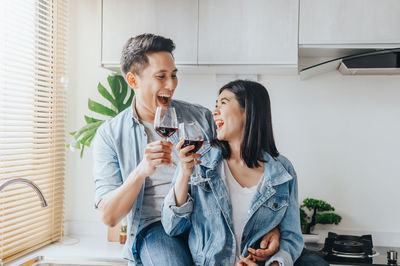 Happy couple holding wineglasses at home