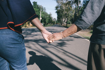 Midsection of woman holding grandmother hands on street