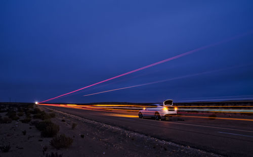 Light trails on road against clear sky at night