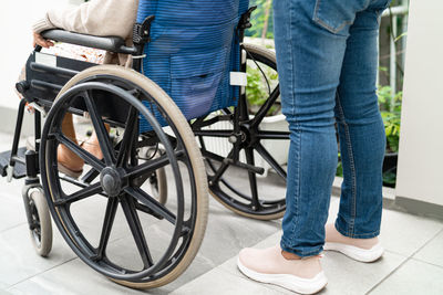 Low section of man standing on wheelchair
