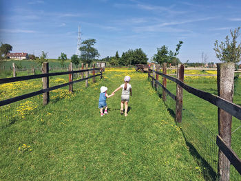 People on field by railing against sky